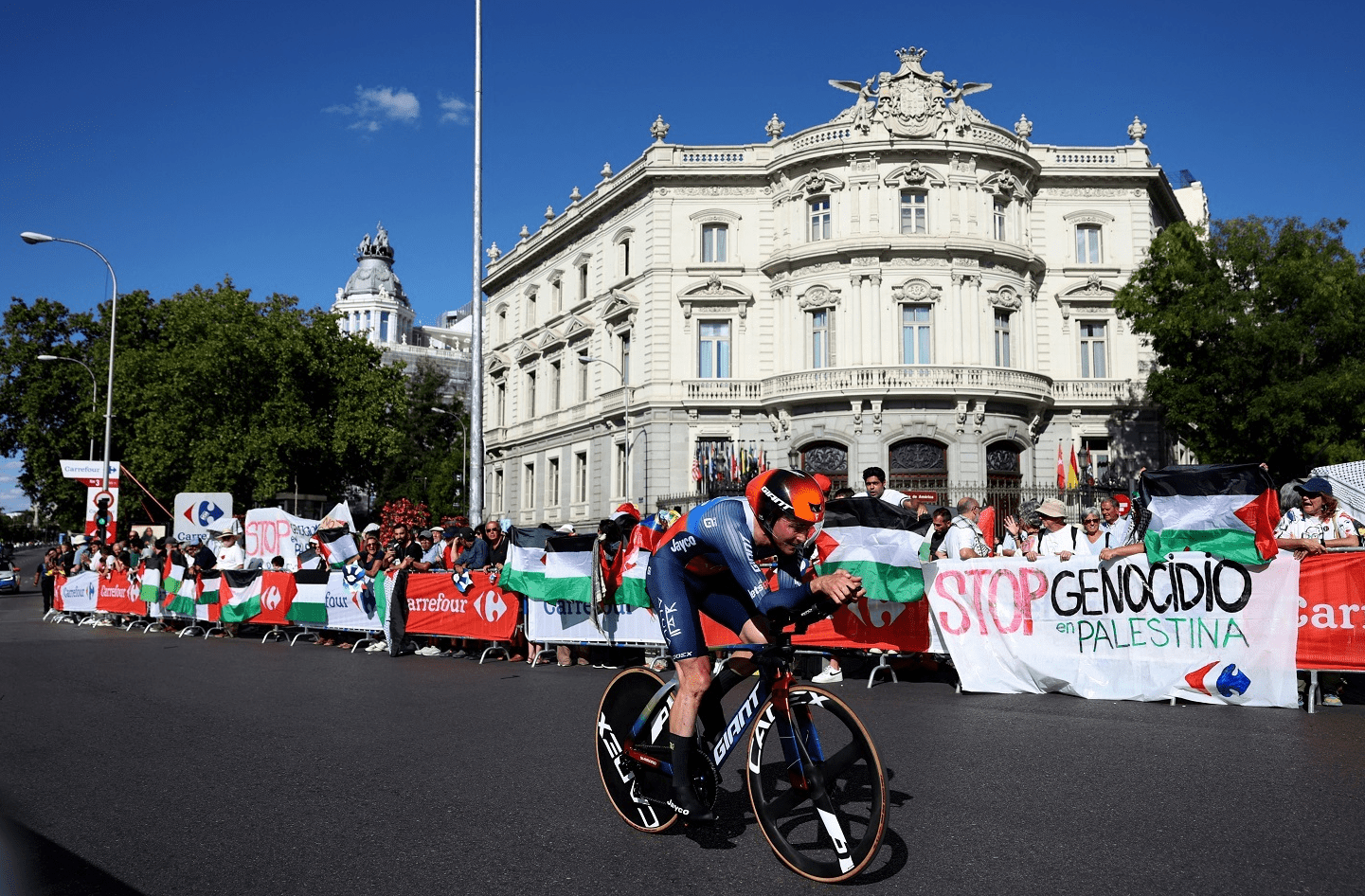 Ciclista de La Vuelta a España y manifestantes con banderas palestinas